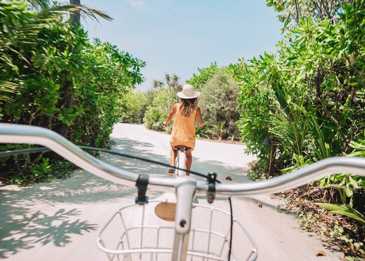 People riding bicycles on a road with trees