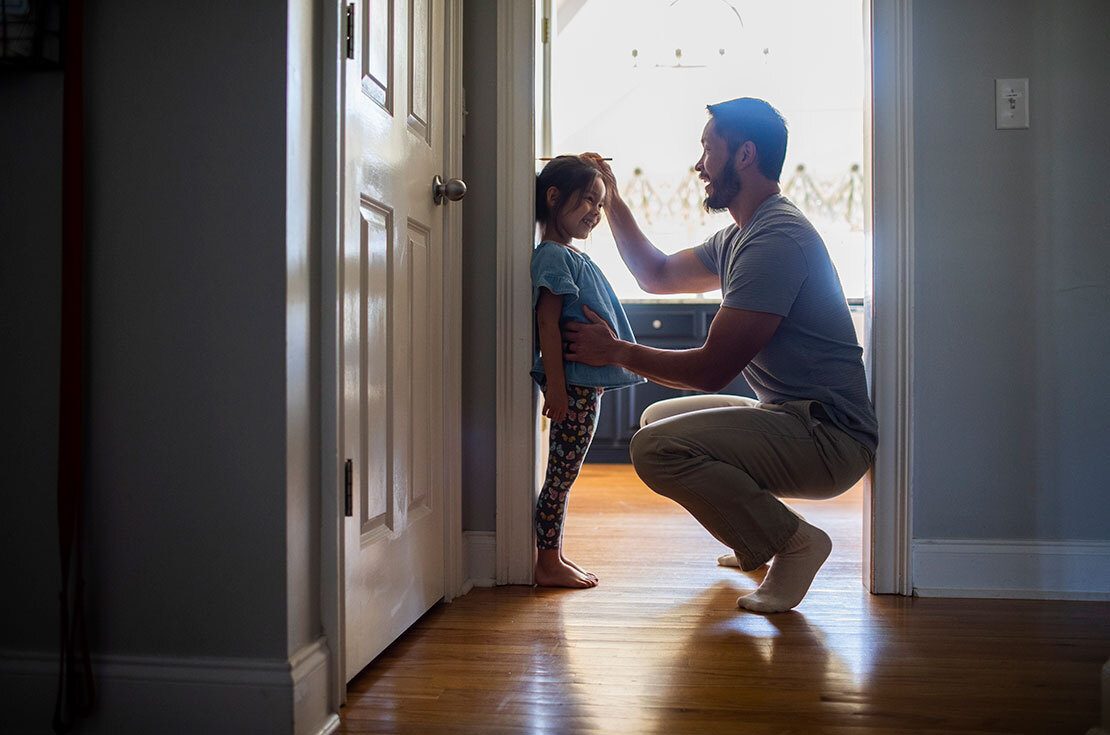 A father measuring daughter's height against a wall