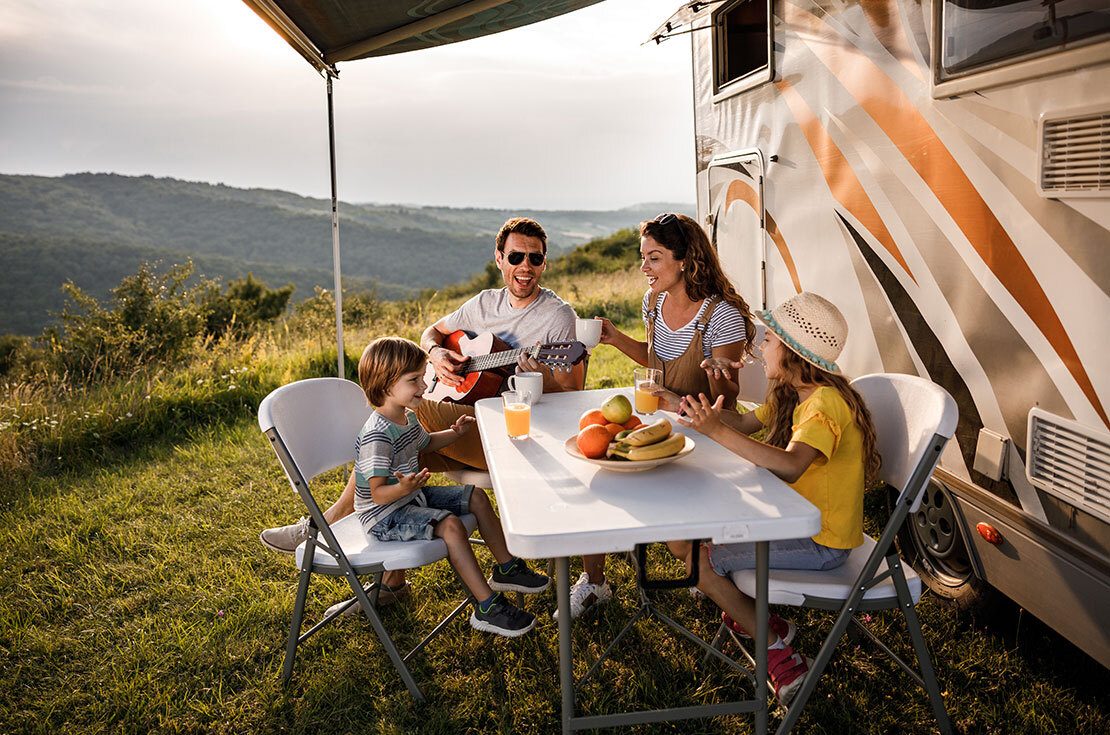 Happy family signing during their camping day by the trailer